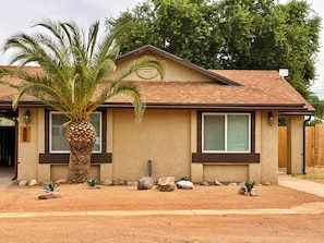 A single-story house with a brown roof, beige walls, and a palm tree in the front yard. - WINTER ESCAPE- PET-FRIENDLY 3BD+OFFICE NEAR GOLF COURSES, RIVER AND CASINOS (Mohave Valley)