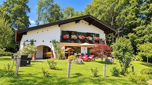 Ein zweistöckiges Haus mit Balkon, überdachter Terrasse und gepflegtem Garten.