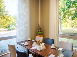 Una sala conferenze con un lungo tavolo, sedie e vista su un parco attraverso ampie finestre.