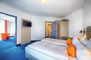 Una camera d'albergo con un letto grande, una televisione, una scrivania e una sedia.