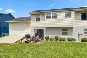 A two-story residential building with a garage, a patio with outdoor furniture, and a well-maintained lawn. - Spacious 5BR Home for Families & Groups (Fort Washington)