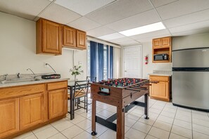 A kitchen with wooden cabinets, a foosball table, a stainless steel refrigerator, and a microwave. - Spacious 5BR Home for Families & Groups (Fort Washington)
