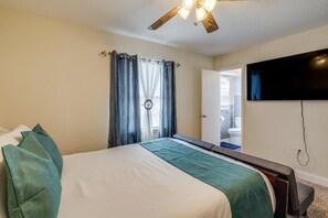 A bedroom with a bed, a ceiling fan, a TV mounted on the wall, and a bathroom visible through an open door. - Amazing 5-bedroom house with AC in charming MD minutes from DC and VA (Fort Washington)