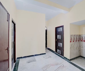 A hallway with a marble floor, beige walls, and a dark wooden door.