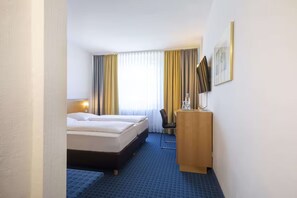 Ein Hotelzimmer mit einem Bett, einem Schreibtisch, einem Sessel und einem Fernseher.