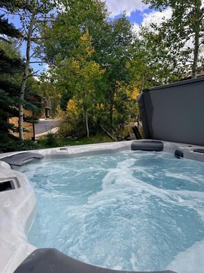 An outdoor hot tub surrounded by trees and a building. - Downtown WP Townhome 108 I Private Hot Tub I Great Views I Bunk Room I Discounted Attractions (Winter Park)