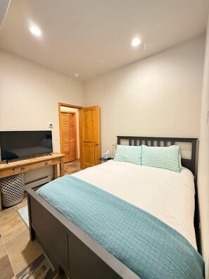 A bedroom with a bed, a TV, a desk, and a door. - Downtown WP Townhome 108 I Private Hot Tub I Great Views I Bunk Room I Discounted Attractions (Winter Park)
