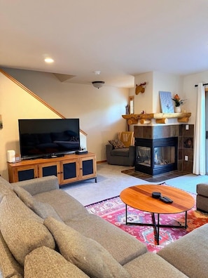 Una sala de estar con una televisión de pantalla plana grande, una chimenea, un sofá y una mesa de centro.