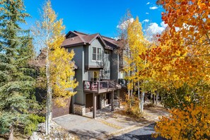 Ein zweistöckiges Haus mit Balkon, umgeben von Bäumen im Herbstlaub.