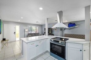A modern kitchen with white cabinetry, a built-in oven, and a stainless steel range hood. - Heated Private Pool House Minutes From Indian Rocks Beach (Largo)