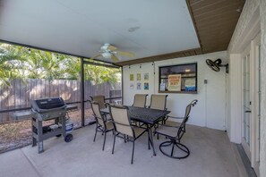 A covered patio with a grill, table, chairs, and a ceiling fan. - Heated Private Pool House Minutes From Indian Rocks Beach (Largo)