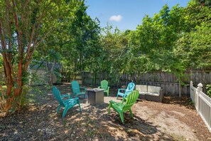 An outdoor patio area with a table and chairs, surrounded by a wooden fence and trees. - Heated Private Pool House Minutes From Indian Rocks Beach (Largo)