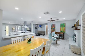 A modern kitchen with a dining area, a ceiling fan, and artwork on the walls. - Heated Private Pool House Minutes From Indian Rocks Beach (Largo)