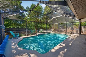 A covered outdoor swimming pool with a safety fence, surrounded by trees and a wooden fence. - Heated Private Pool House Minutes From Indian Rocks Beach (Largo)