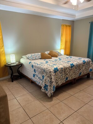 Een slaapkamer met een bed, nachtkastje en gordijnen.