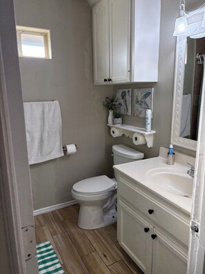 Een badkamer met toilet, wastafel, kastje en een klein raam.