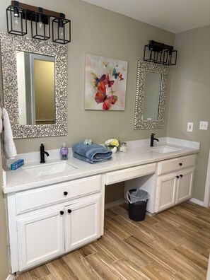 A bathroom with two sinks, a mirror, and a decorative wall piece. - Spacious 4-bedroom house in lovely Weslaco with AC (Weslaco)