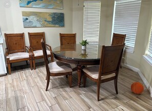 A dining area with a round table, six wooden chairs, and a potted plant. - Spacious 4-bedroom house in lovely Weslaco with AC (Weslaco)