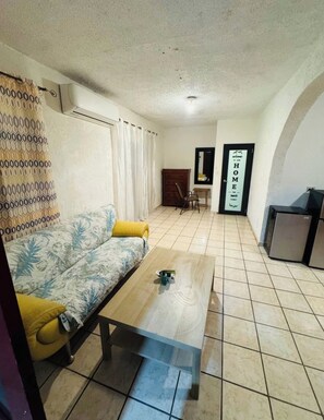 A living room with a sofa, a coffee table, a TV, and a refrigerator. - Huesca House next to Airport (San Juan)