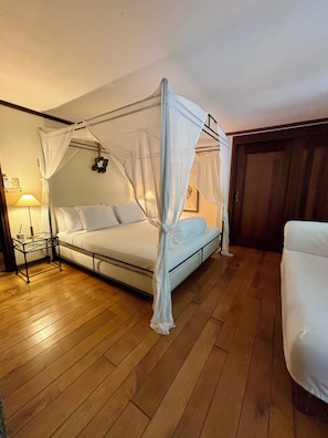 A bedroom with a four-poster bed, a bedside table, a lamp, and a wooden floor. - Haiku House on Saba Island - The unspoiled Queen of the Caribbean (Saba)