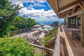 A wooden deck with outdoor furniture, a pool, and a view of the ocean.