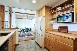 A modern kitchen with wooden cabinets, a built-in oven, and a dining area with a rug. - Water & Gulf Islands Views, Beach Access, Hot Tub, Game Room (Bellingham)