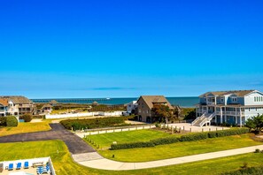 A coastal residential area with houses, a clear sky, and a view of the sea. - Sunrise Symphony  pool, ocean views, and beach access (Duck)
