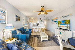 A living room with a sofa, a coffee table, a TV, and a ceiling fan. - Sunrise Symphony  pool, ocean views, and beach access (Duck)