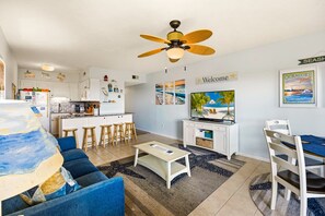 A living room with a sofa, coffee table, TV, and a ceiling fan. - Sunrise Symphony  pool, ocean views, and beach access (Duck)