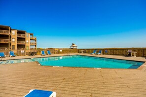 A swimming pool with lounge chairs and a wooden deck. - Sunrise Symphony  pool, ocean views, and beach access (Duck)
