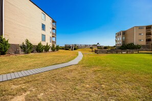 A residential area with a pathway leading to a building with multiple balconies. - Sunrise Symphony  pool, ocean views, and beach access (Duck)