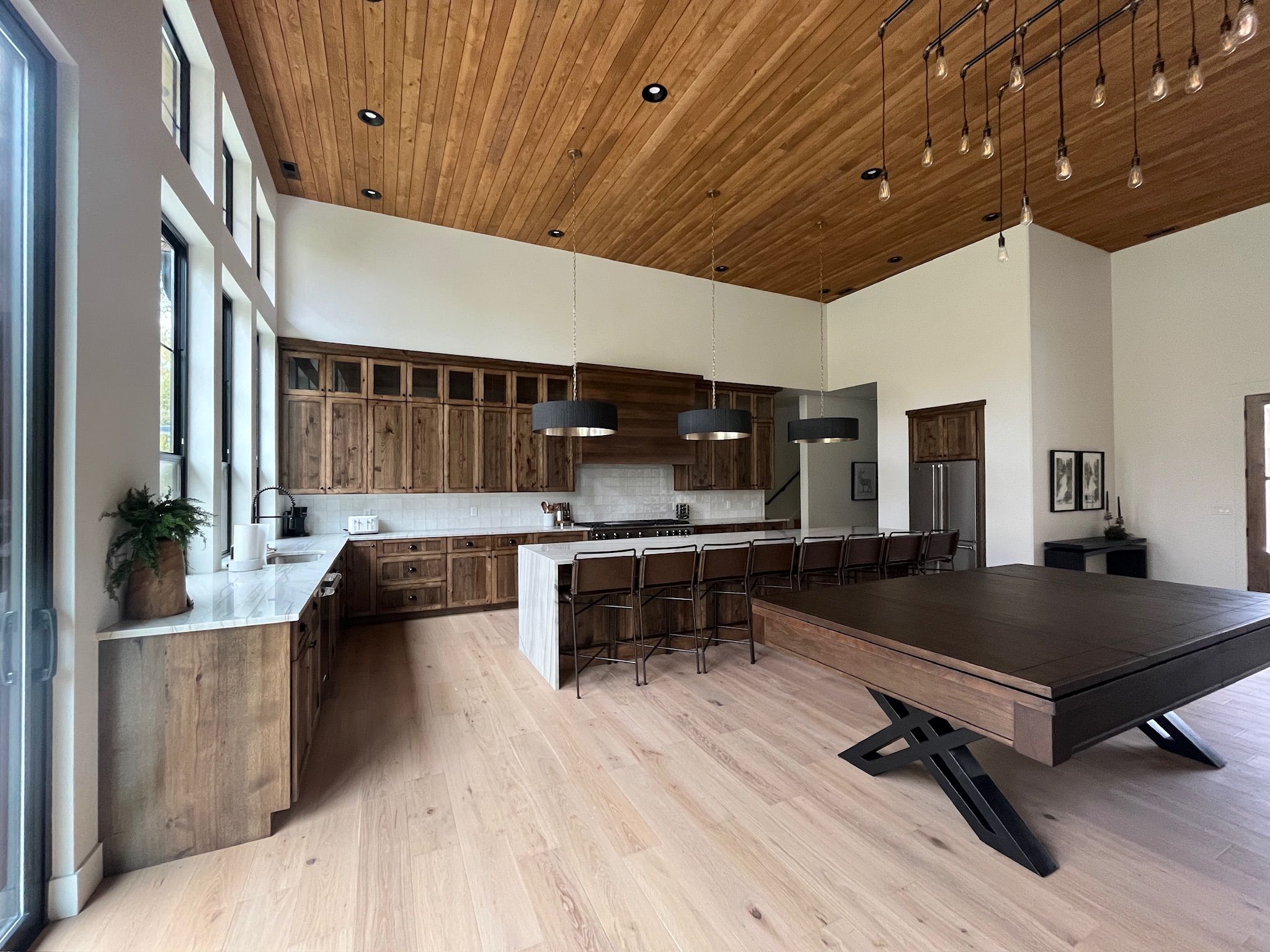 A modern kitchen with wooden cabinets, a central island, and pendant lighting.
