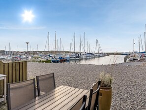 Ein Yachthafen mit vertäuten Booten, ein Holzdeck mit Sitzgelegenheiten und ein klarer Himmel.