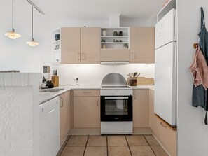 Eine kompakte Küche mit einem Bosch-Ofen, einem eingebauten Geschirrspüler und einem weißen Kühlschrank.