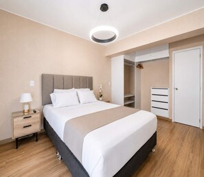 Een moderne slaapkamer met een bed, nachtkastje, lamp en een inloopkast.