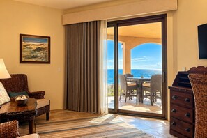 Ein Hotelzimmer mit Essbereich, Meerblick und einer großen Schiebeglastür.