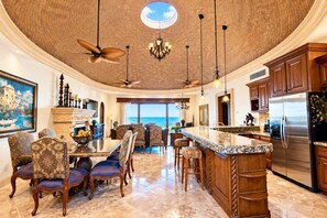 A spacious kitchen with a large island, a dining area with chairs, and a view of the ocean. - Front Row to the Beach - 5 BR Bella Sirena Villa (Puerto Peñasco)
