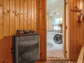 A wooden interior with a fireplace, a washing machine, and a kitchen area visible through an open door. - "Aisa" - 200m from the sea by Interhome (Ebeltoft)