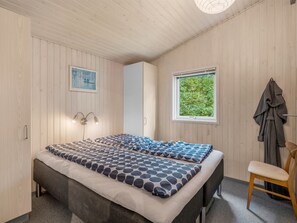 Une pièce comprenant un lit, une chaise, une fenêtre et un porte-manteau.