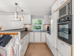 A modern kitchen with white cabinetry, a central island, a built-in oven, and pendant lighting. - "Aisa" - 200m from the sea by Interhome (Ebeltoft)