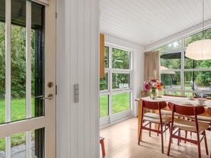 Un comedor con una mesa dispuesta para cuatro personas, ventanas amplias y vistas al jardín.