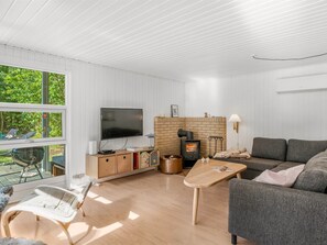 A modern living room with a flat-screen TV, a fireplace, a sofa, and a dining area with a table. - "Aisa" - 200m from the sea by Interhome (Ebeltoft)