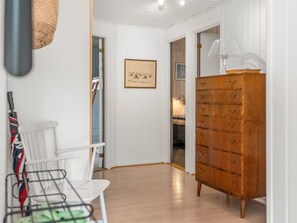 A hallway with a wooden dresser, a framed picture on the wall, and a chair with a metal frame. - "Aisa" - 200m from the sea by Interhome (Ebeltoft)