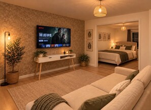 A modern living room with a flat-screen TV, a sofa, a coffee table, and a bedside table with a lamp. - Stevenage Studios - Studio 3 (Stevenage)