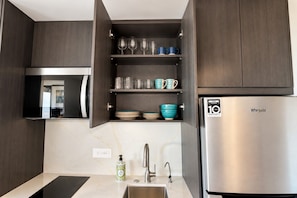 A modern kitchen with dark wood cabinets, a stainless steel refrigerator, and a built-in wine rack. - 15th Floor Stunning Studio Condo in Sonoran Star (Puerto Peñasco)