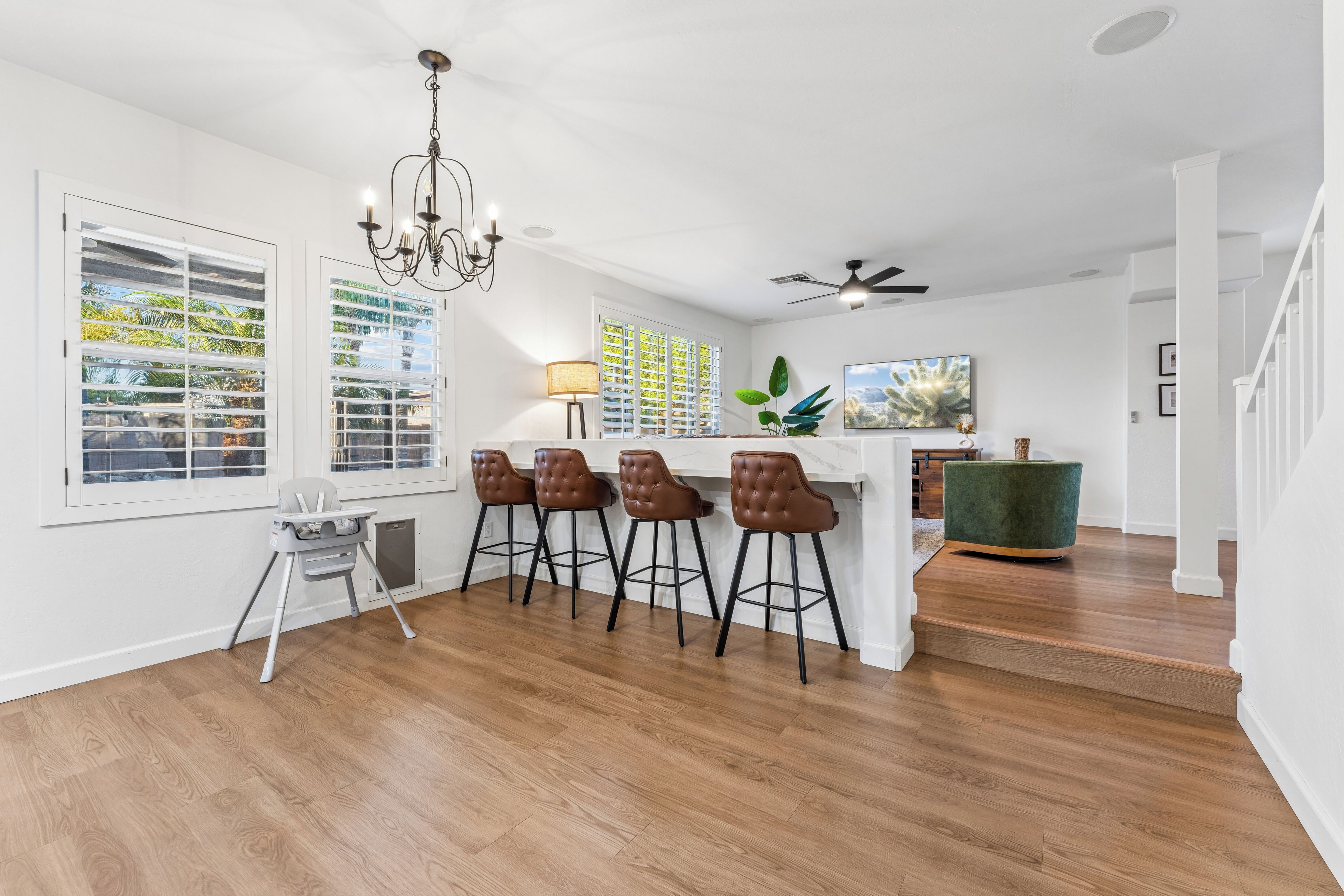 A modern kitchen with a bar area, wooden flooring, and a ceiling fan.