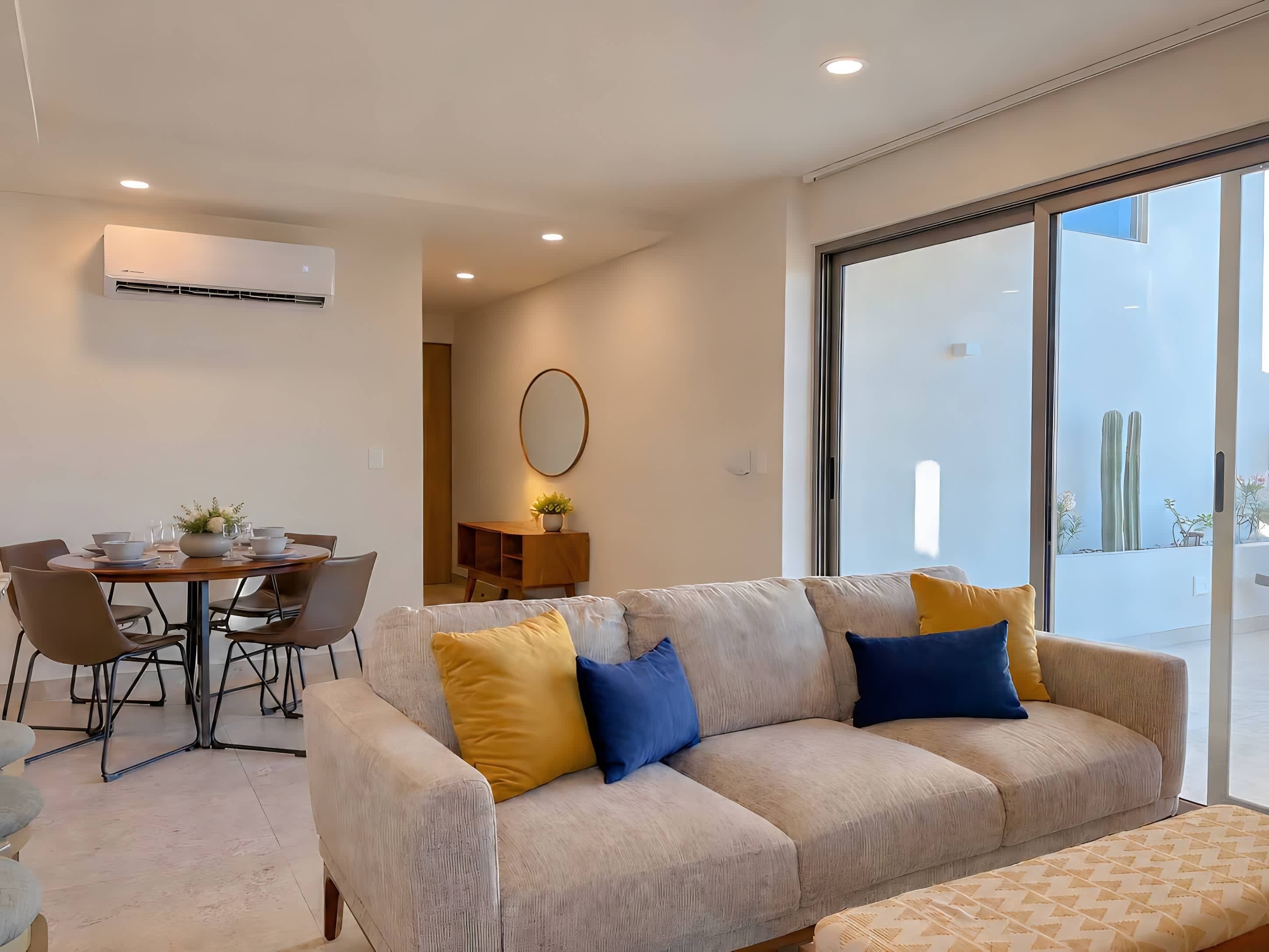 A modern living room with a sofa, dining table, and chairs.