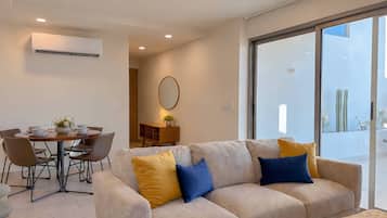 A modern living room with a sofa, dining table, and chairs.