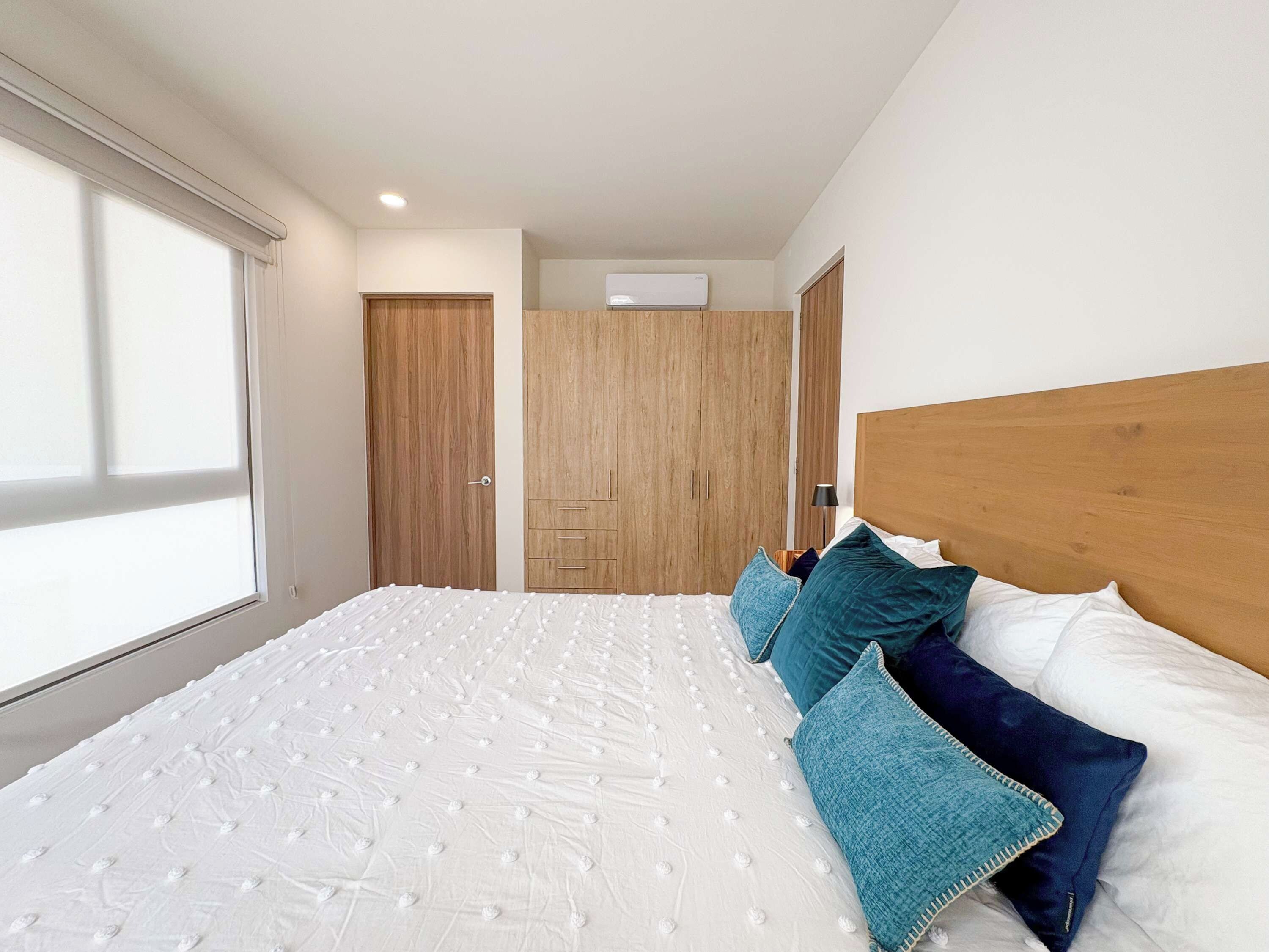 Un dormitorio con una cama grande, un armario de madera y una ventana.