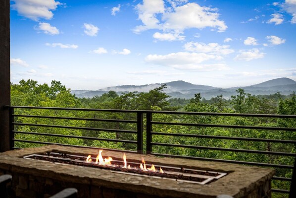 Un balcon agrémenté d’un foyer, offrant une vue sur un paysage montagneux.